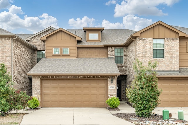 townhome / multi-family property with an attached garage, a shingled roof, concrete driveway, and brick siding