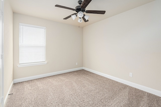 carpeted spare room featuring baseboards and a ceiling fan