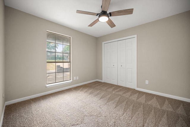 unfurnished bedroom featuring carpet, a closet, baseboards, and ceiling fan