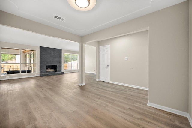 unfurnished living room featuring baseboards, wood finished floors, visible vents, and a fireplace