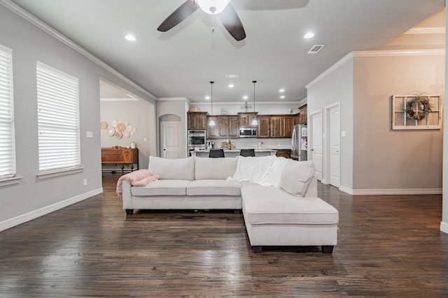 living room featuring a ceiling fan, ornamental molding, dark wood-type flooring, and visible vents