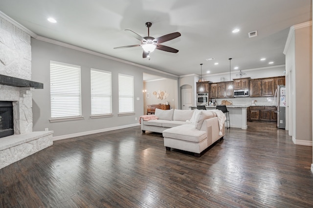 living room with a ceiling fan, dark wood finished floors, crown molding, and visible vents
