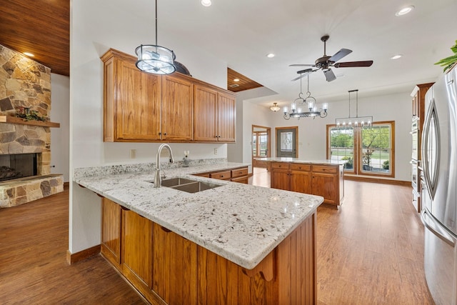 kitchen featuring a center island, wood finished floors, a sink, and a peninsula