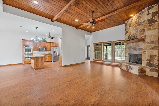 unfurnished living room featuring light wood-style flooring, baseboards, a fireplace, beam ceiling, and ceiling fan with notable chandelier