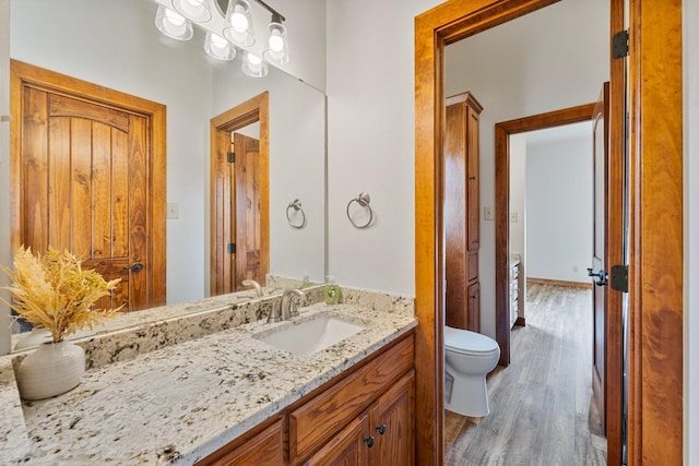 bathroom featuring toilet, wood finished floors, and vanity