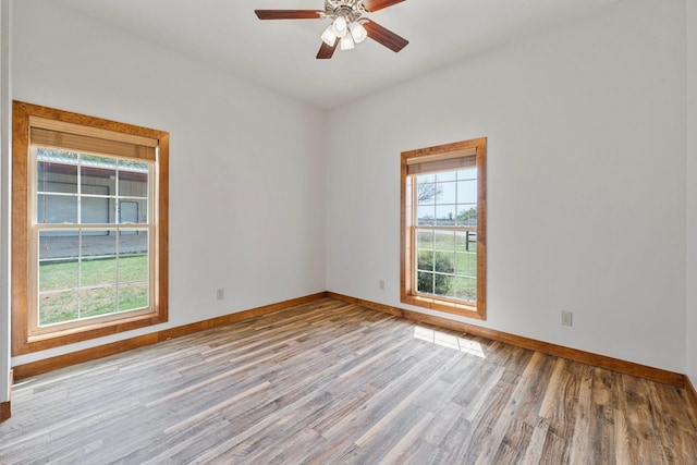 spare room featuring baseboards, wood finished floors, and ceiling fan