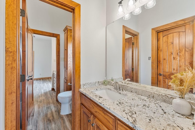 bathroom with toilet, wood finished floors, and vanity