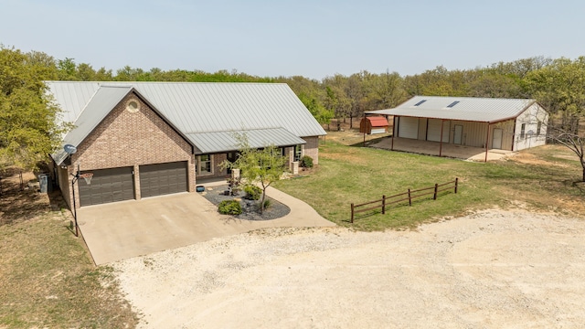 view of front of home featuring metal roof, a garage, brick siding, a front lawn, and driveway