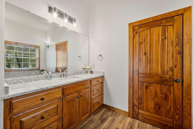 bathroom with baseboards, wood finished floors, and vanity