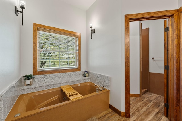 bathroom with baseboards, a garden tub, and wood finished floors