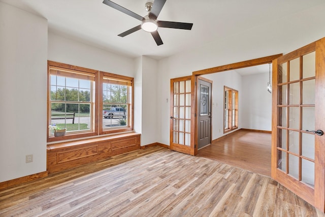 unfurnished room with baseboards, ceiling fan, wood finished floors, and french doors