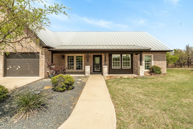 view of front of home with concrete driveway, metal roof, a front lawn, brick siding, and a garage
