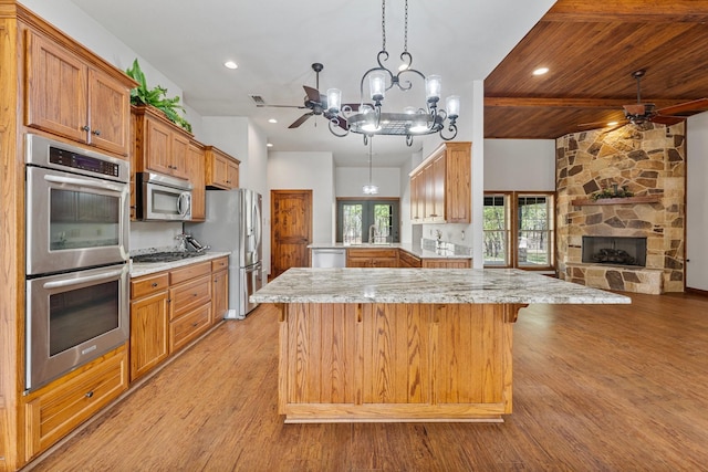 kitchen featuring open floor plan, light wood-type flooring, stainless steel appliances, ceiling fan with notable chandelier, and a kitchen island