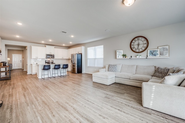living area with recessed lighting, baseboards, light wood-style floors, and visible vents