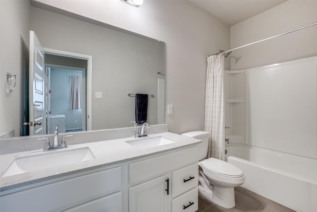 bathroom featuring toilet, a sink, double vanity, and tile patterned flooring