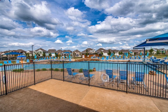 view of swimming pool with a residential view, fence, and a patio