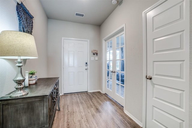 foyer featuring baseboards, light wood finished floors, and visible vents