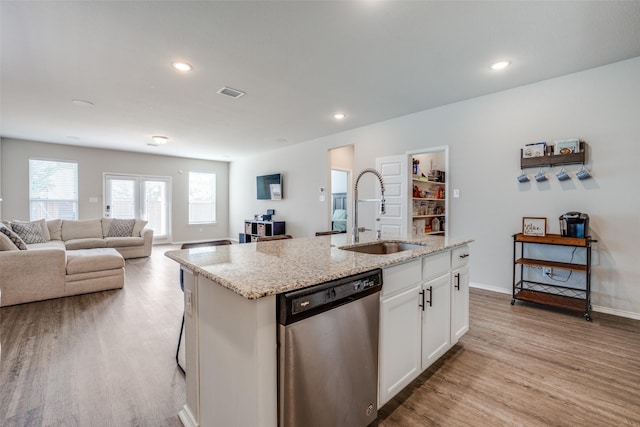 kitchen featuring light stone countertops, a sink, visible vents, dishwasher, and a kitchen island with sink