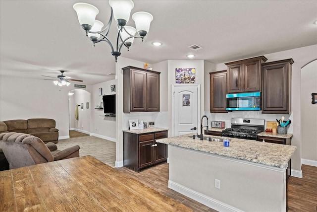 kitchen with dark brown cabinetry, arched walkways, visible vents, appliances with stainless steel finishes, and a sink