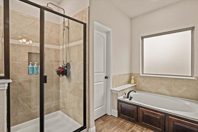 full bath featuring a shower stall, wood finished floors, and a garden tub
