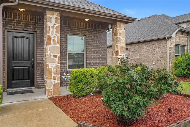 entrance to property with brick siding, roof with shingles, and stone siding