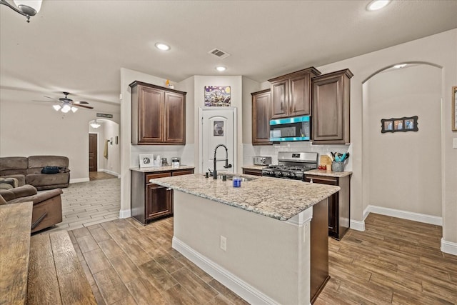 kitchen with a ceiling fan, visible vents, stainless steel appliances, arched walkways, and a sink