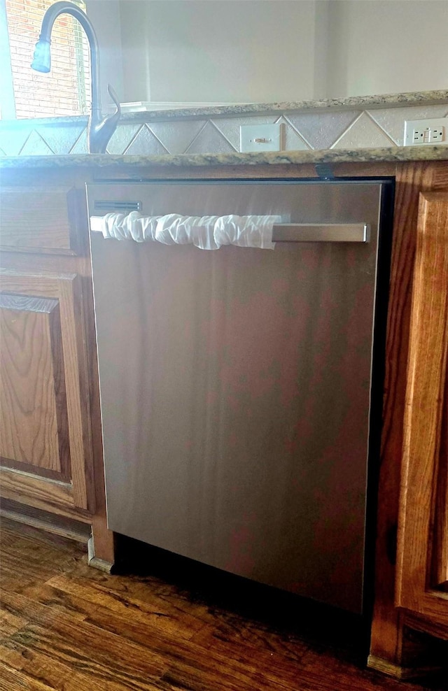 interior details featuring dark wood-type flooring, stainless steel dishwasher, and brown cabinetry