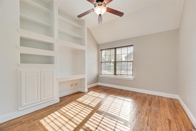 spare room with baseboards, a ceiling fan, vaulted ceiling, and wood finished floors