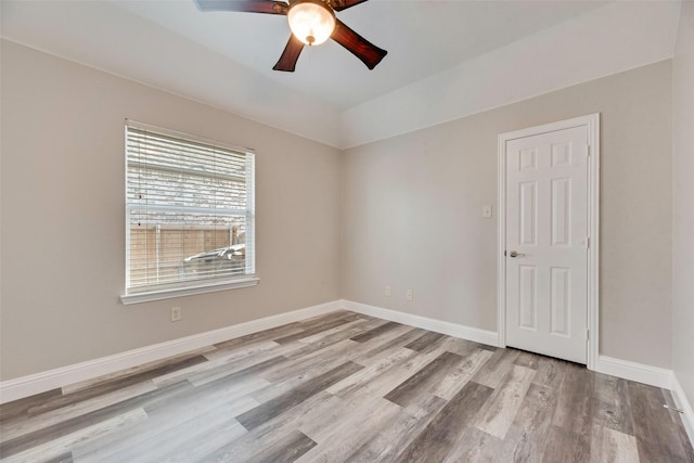 empty room with ceiling fan, wood finished floors, and baseboards