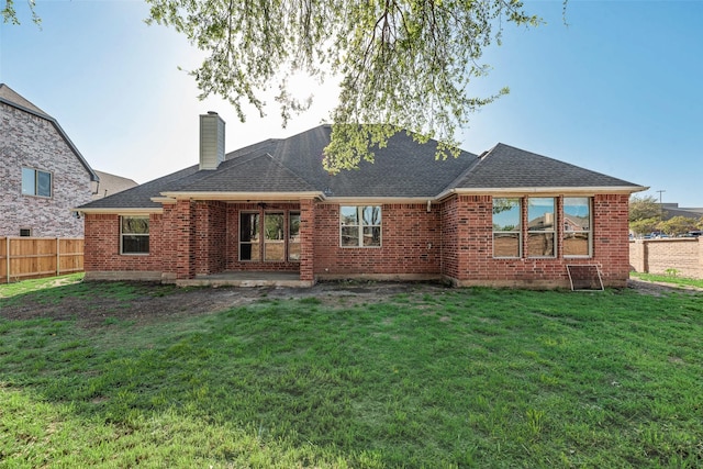 rear view of house with a yard, a shingled roof, fence, and brick siding