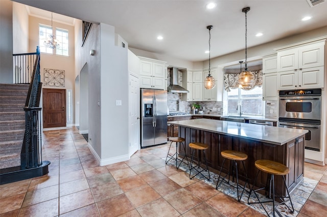 1179 Marquette Dr, Frisco, TX 75033 - kitchen with stainless steel appliances, wall chimney exhaust hood, a sink, backsplash, and a kitchen breakfast bar