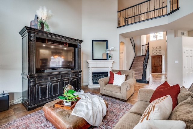 1179 Marquette Dr, Frisco, TX 75033 - tiled living room featuring a high ceiling, stairs, baseboards, and a glass covered fireplace