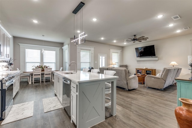 kitchen featuring wood finished floors, appliances with stainless steel finishes, a kitchen bar, a sink, and visible vents