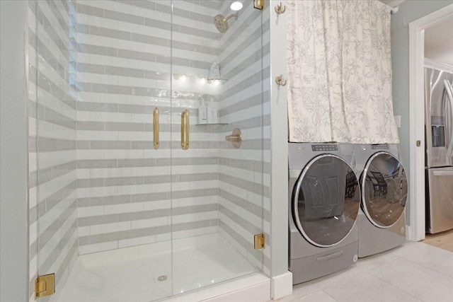 bathroom with tile patterned floors, washer and clothes dryer, and a stall shower