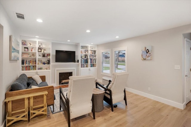 living room with light wood finished floors, baseboards, a fireplace, and recessed lighting