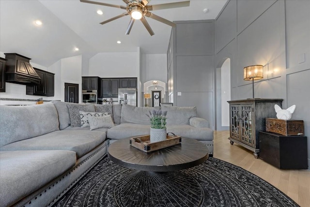 living area featuring light wood finished floors, arched walkways, high vaulted ceiling, a ceiling fan, and recessed lighting