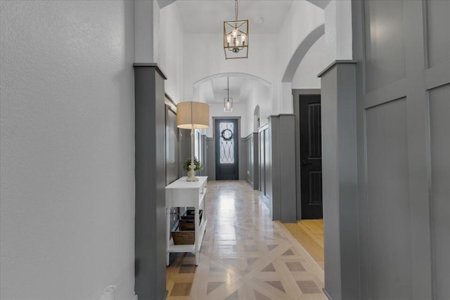 hallway with an inviting chandelier and arched walkways