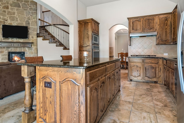 6417 Belhaven Dr, Fort Worth, TX 76123 - kitchen featuring under cabinet range hood, decorative backsplash, open floor plan, a center island, and appliances with stainless steel finishes