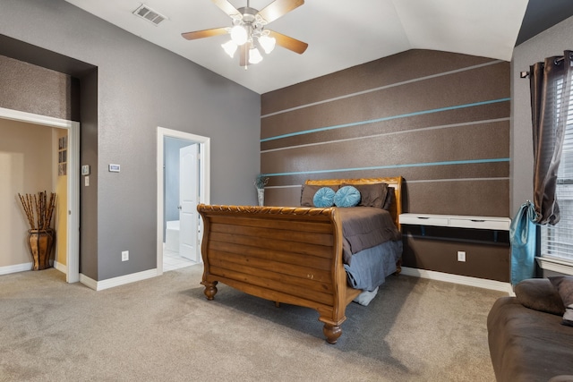 carpeted bedroom featuring lofted ceiling, baseboards, ensuite bath, visible vents, and a ceiling fan