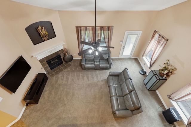 carpeted living room with a tiled fireplace, baseboards, and ceiling fan