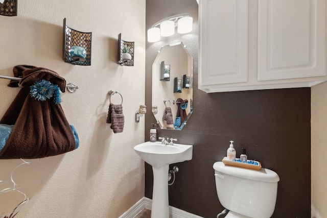 half bathroom featuring baseboards and toilet