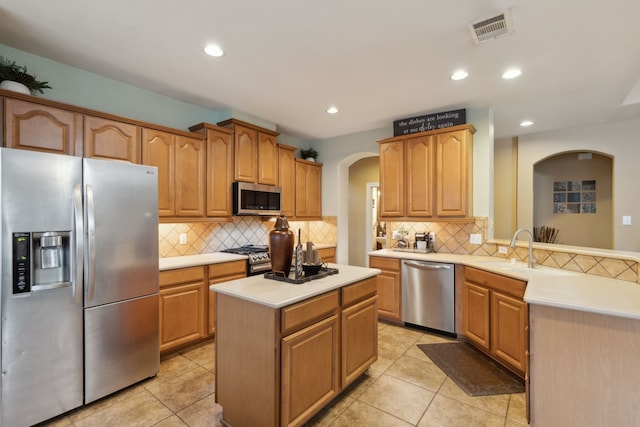 kitchen with light countertops, a sink, appliances with stainless steel finishes, visible vents, and arched walkways