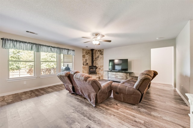207 Shady Oaks Dr, Runaway Bay, TX 76426 - living area featuring ceiling fan, a wood stove, a textured ceiling, visible vents, and light wood finished floors