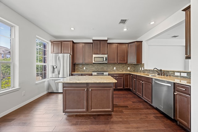 kitchen with visible vents, a center island, a sink, stainless steel appliances, and dark wood-type flooring