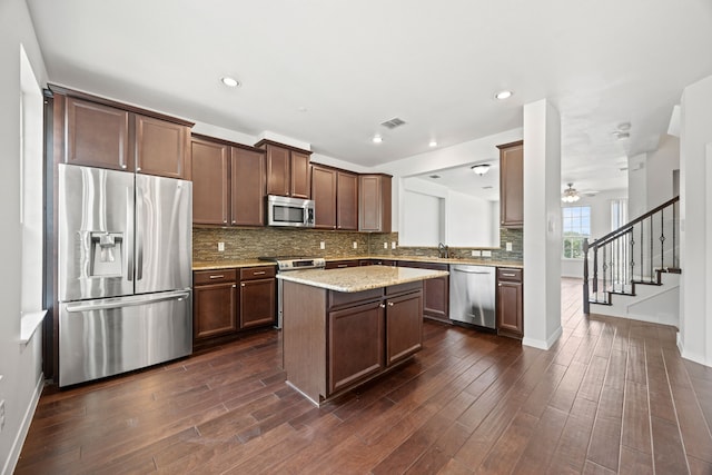 kitchen with backsplash, stainless steel appliances, dark wood-style floors, and a kitchen island