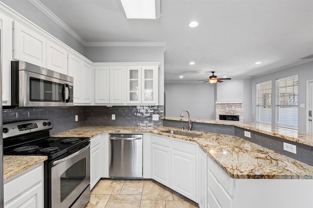 729 Ridgeway Blvd, Weatherford, TX 76086 - kitchen featuring stainless steel appliances, a sink, ceiling fan, a stone fireplace, and crown molding