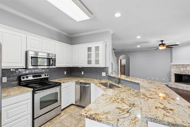 729 Ridgeway Blvd, Weatherford, TX 76086 - kitchen with stainless steel appliances, a peninsula, a sink, backsplash, and ornamental molding