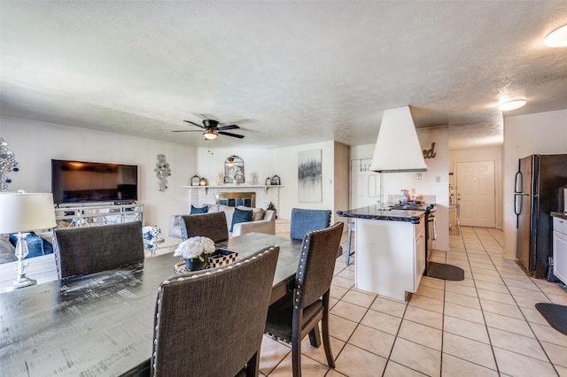 5212 Knox Dr, The Colony, TX 75056 - dining area featuring a glass covered fireplace, light tile patterned floors, a textured ceiling, and ceiling fan