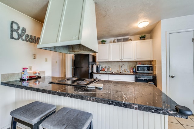 5212 Knox Dr, The Colony, TX 75056 - kitchen featuring exhaust hood, a sink, a peninsula, tile counters, and black appliances