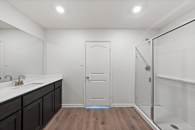 full bath with a stall shower, baseboards, wood finished floors, and vanity
